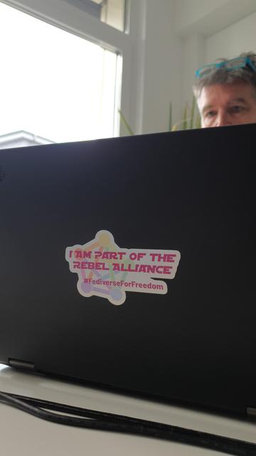Backside of a laptop with a sticker saying "I am part of the rebel alliance" and the hashtag #FediverseFor Freedom