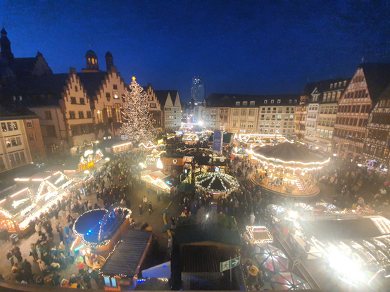 Weihnachtsmarkt in Frankfurt von oben fotografiert. Rechts ist das grosse Karussell zu sehen, links der Baum und dahinter der Römer. In der Mitte mehrere kleinere Weihnachtsmarktstände