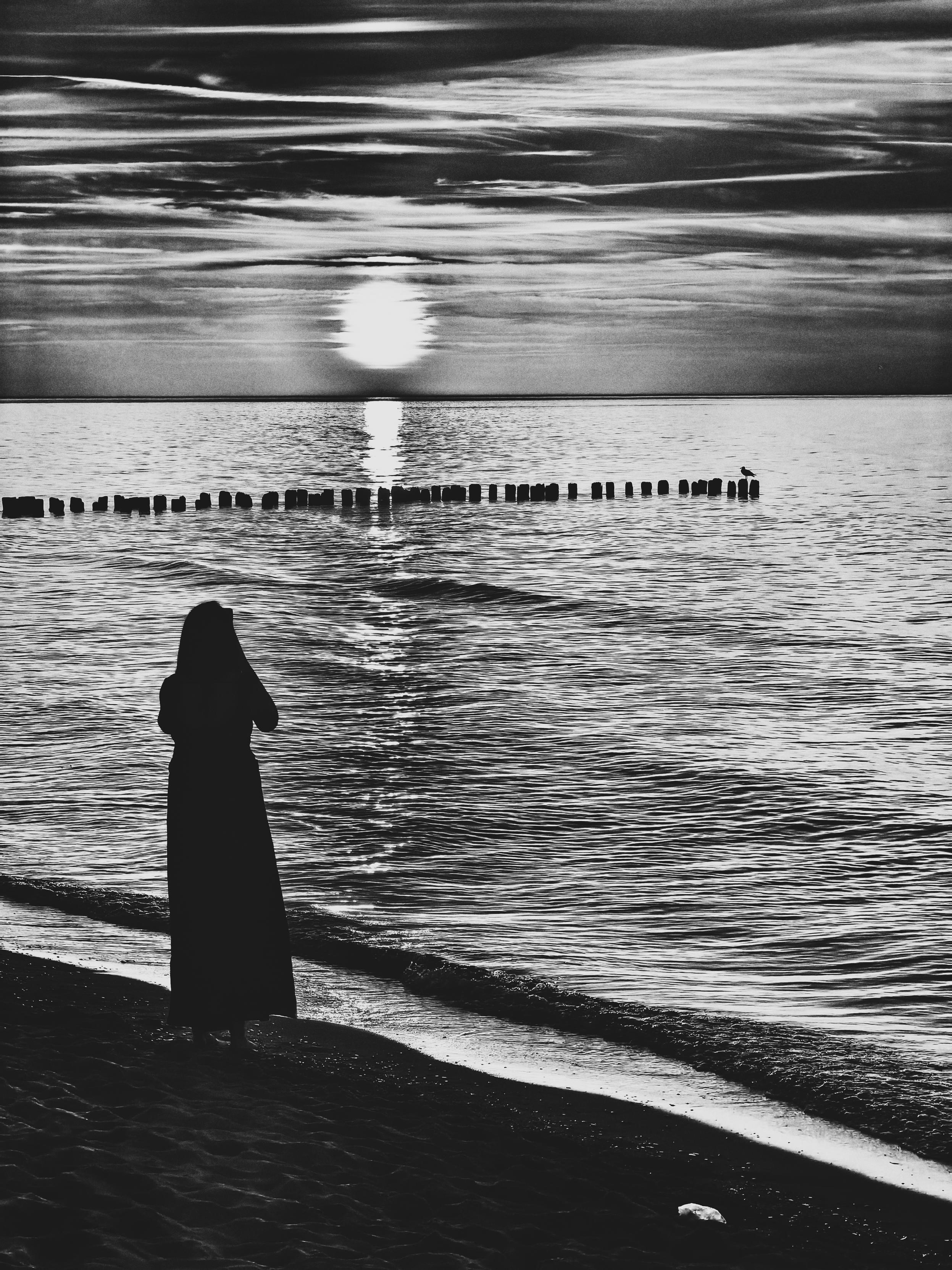Eine Frau am Strand beobachtet den Sonnenuntergang.