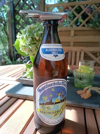 Photo einer Bierflasche auf einem Holztisch. Im Hintergrund sind ein paar Pflanzen zu sehen.
Auf dem Etikett steht "Augustinerbräu München" und "Alkoholfrei Hell"