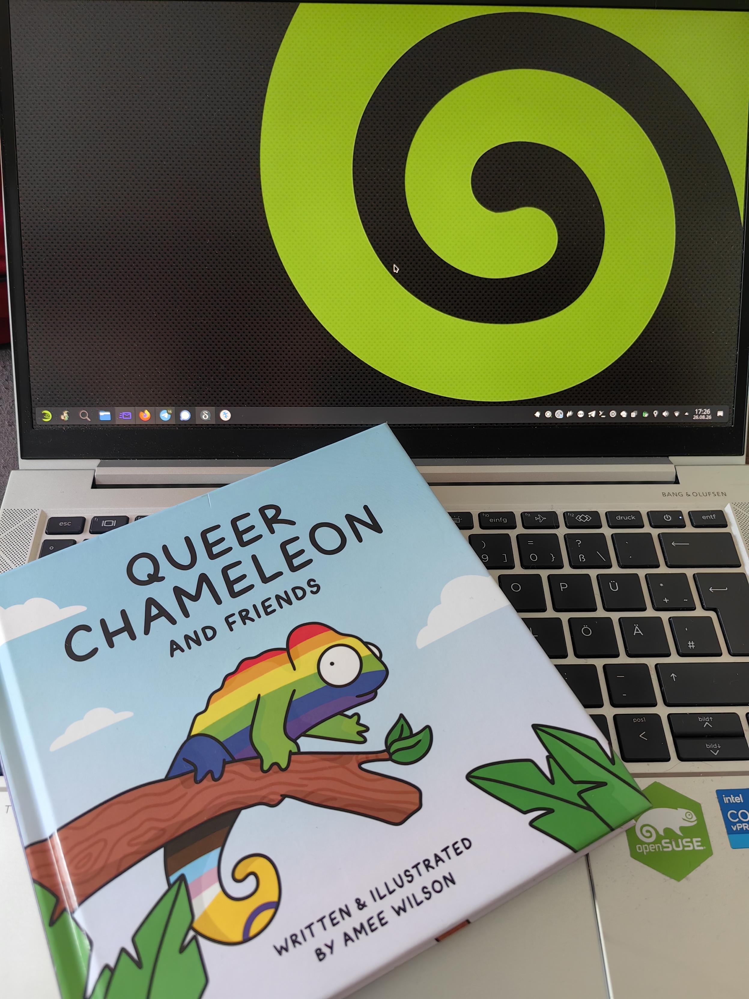 The book "Queer Chameleon" at a Laptop with a chameleons tail set as wallpaper.